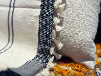 Close-up of a textured fabric with a black stripe and tassels.