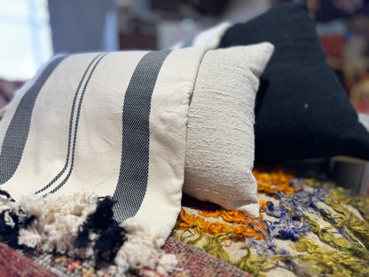 Textured pillow with black and white stripes on a colorful rug