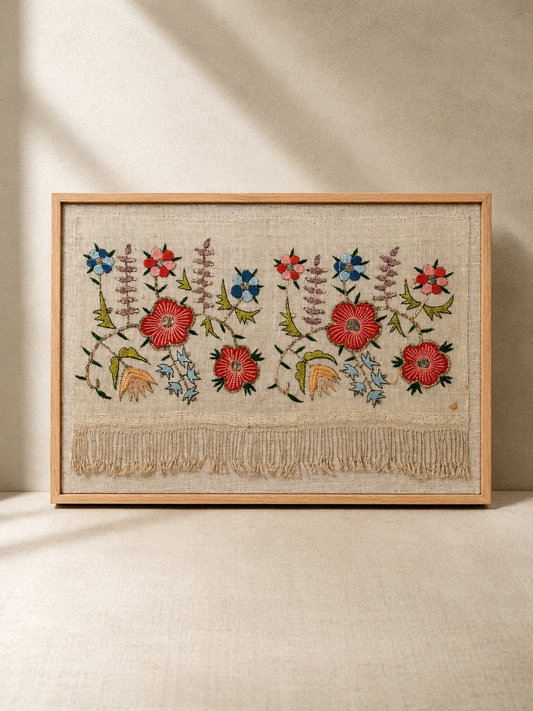 Framed embroidered artwork with floral patterns on a beige background