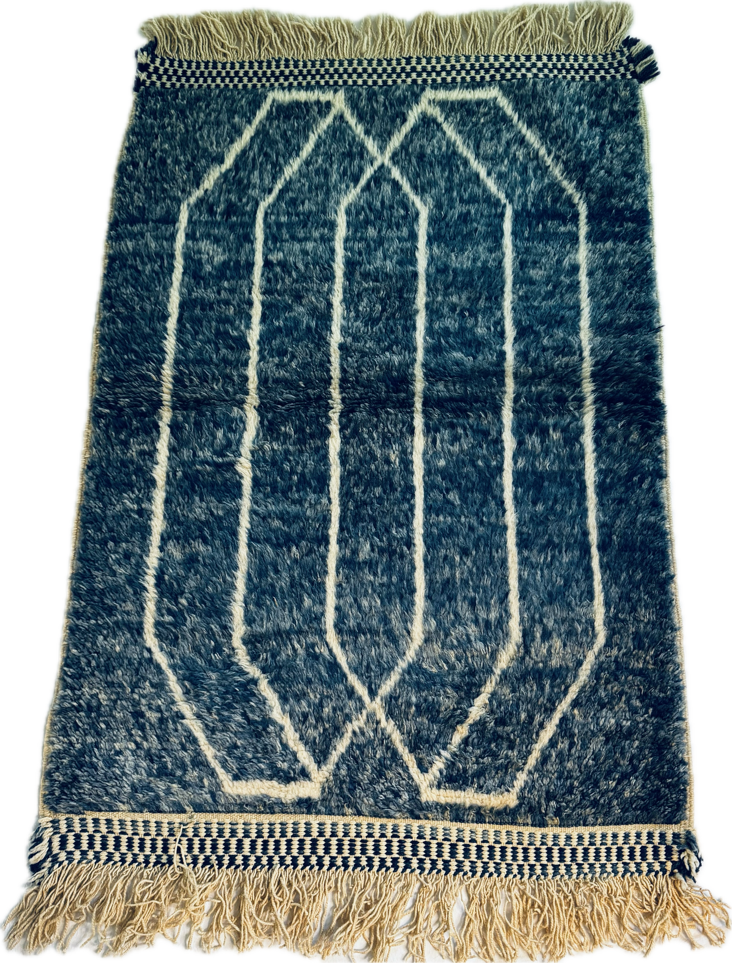 Blue and white geometric patterned rug with fringes on a plain background