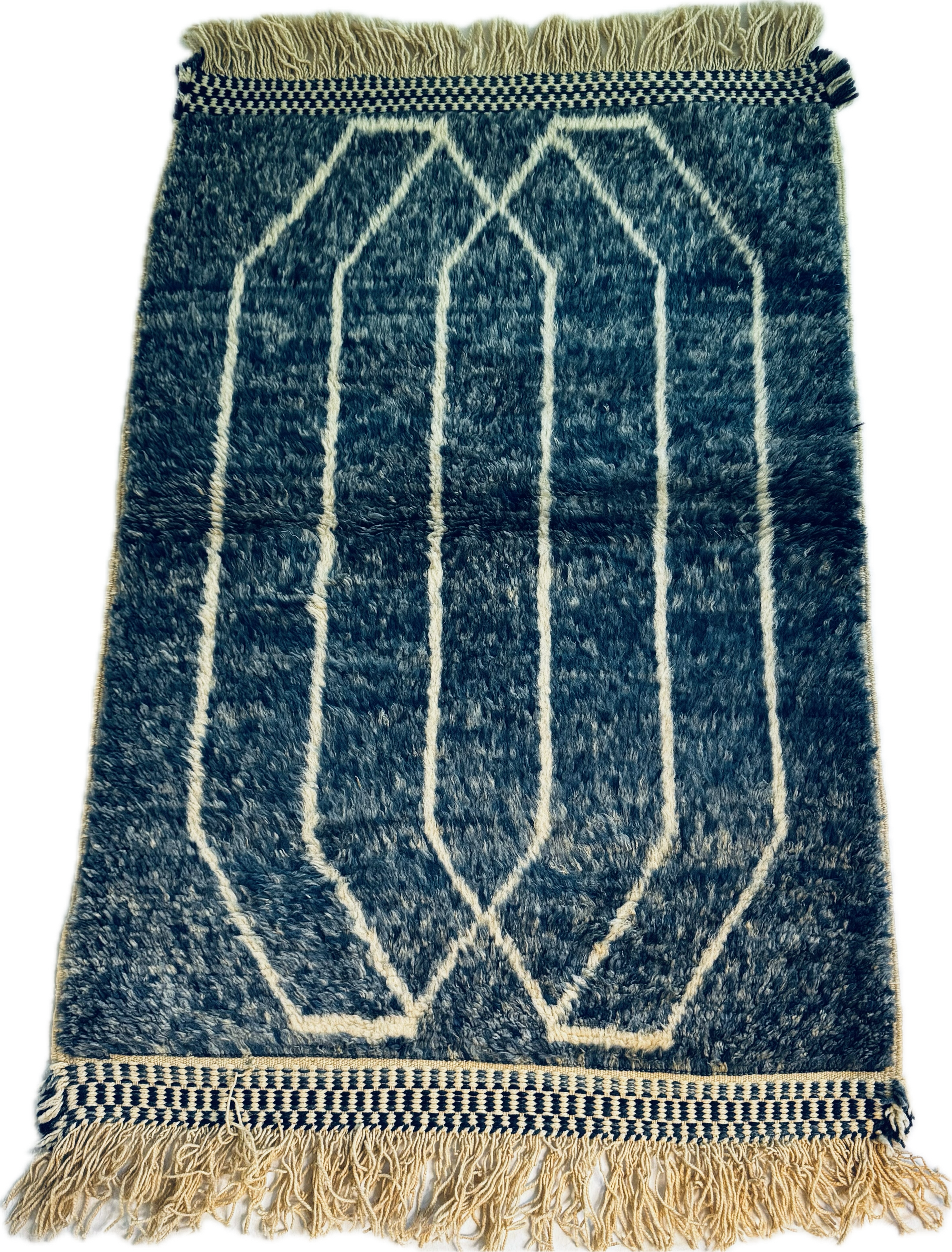 Blue and white geometric patterned rug with fringes on a plain background