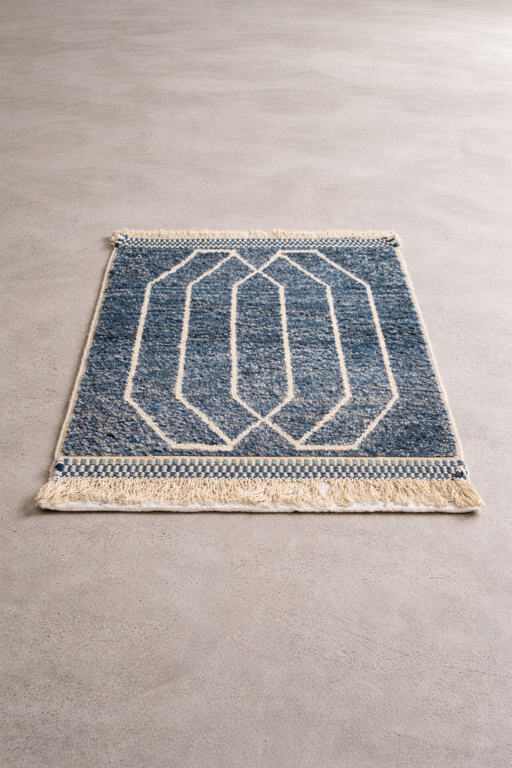 Blue geometric patterned rug with beige border on a gray floor