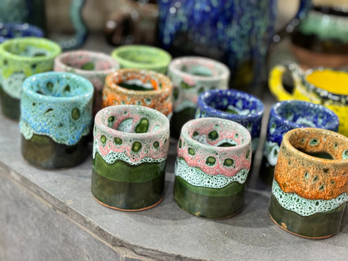 Colorful ceramic cups with textured surfaces on a stone surface