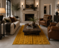 A styled living room featuring a prominent mustard yellow textured area rug under a dark wood coffee table, flanked by a cream sofa and brown leather armchairs.