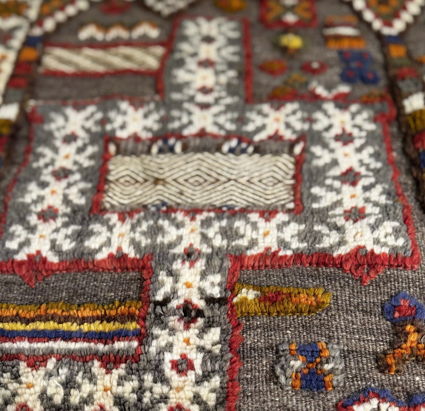 Moroccan Taznakht Kilim close -up of a textured fabric with colorful patterns and designs.