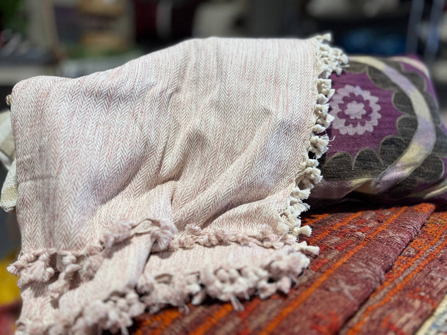 Textured blanket with tassels on a colorful fabric background