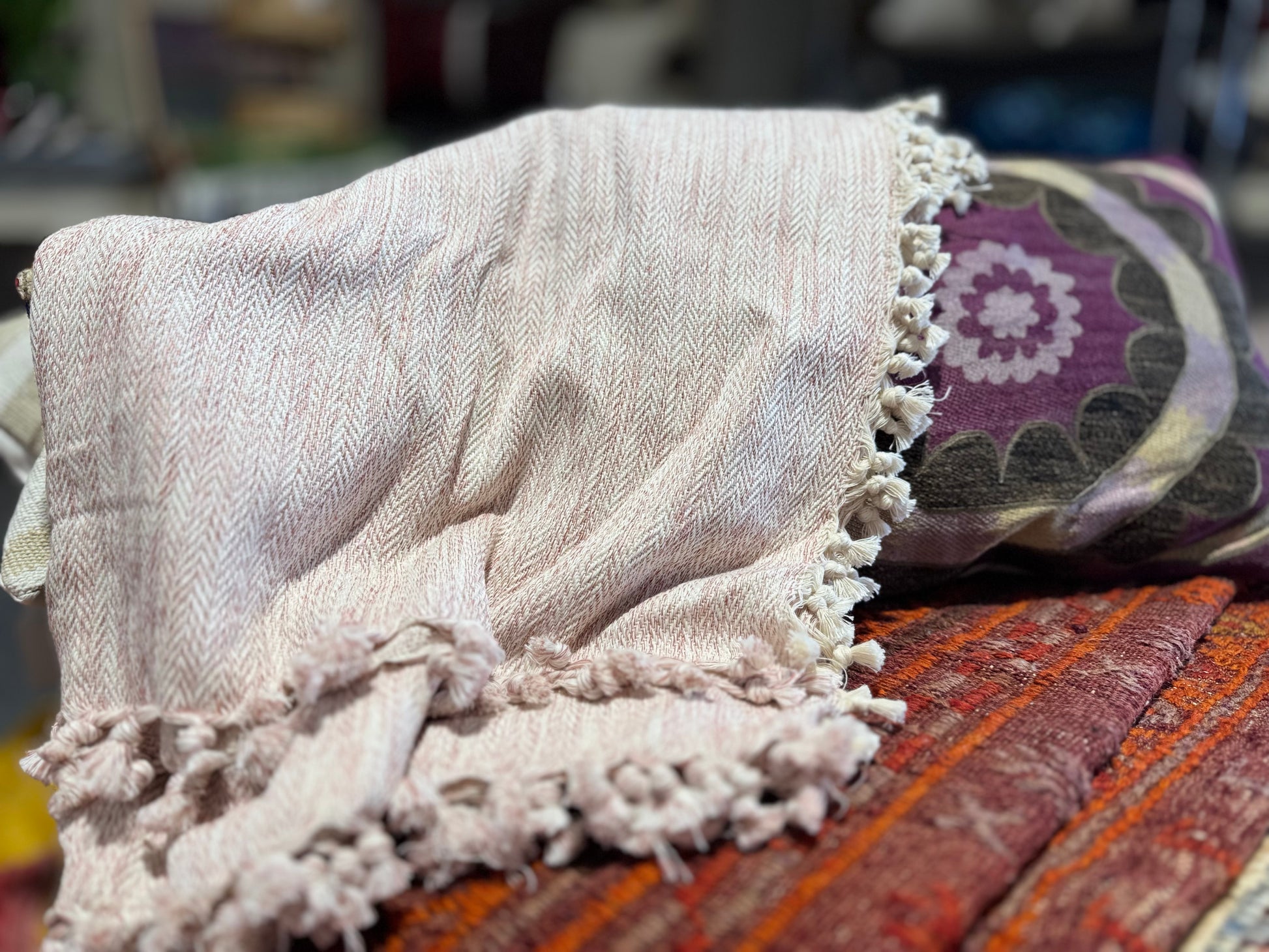 Textured blanket with tassels on a colorful fabric background